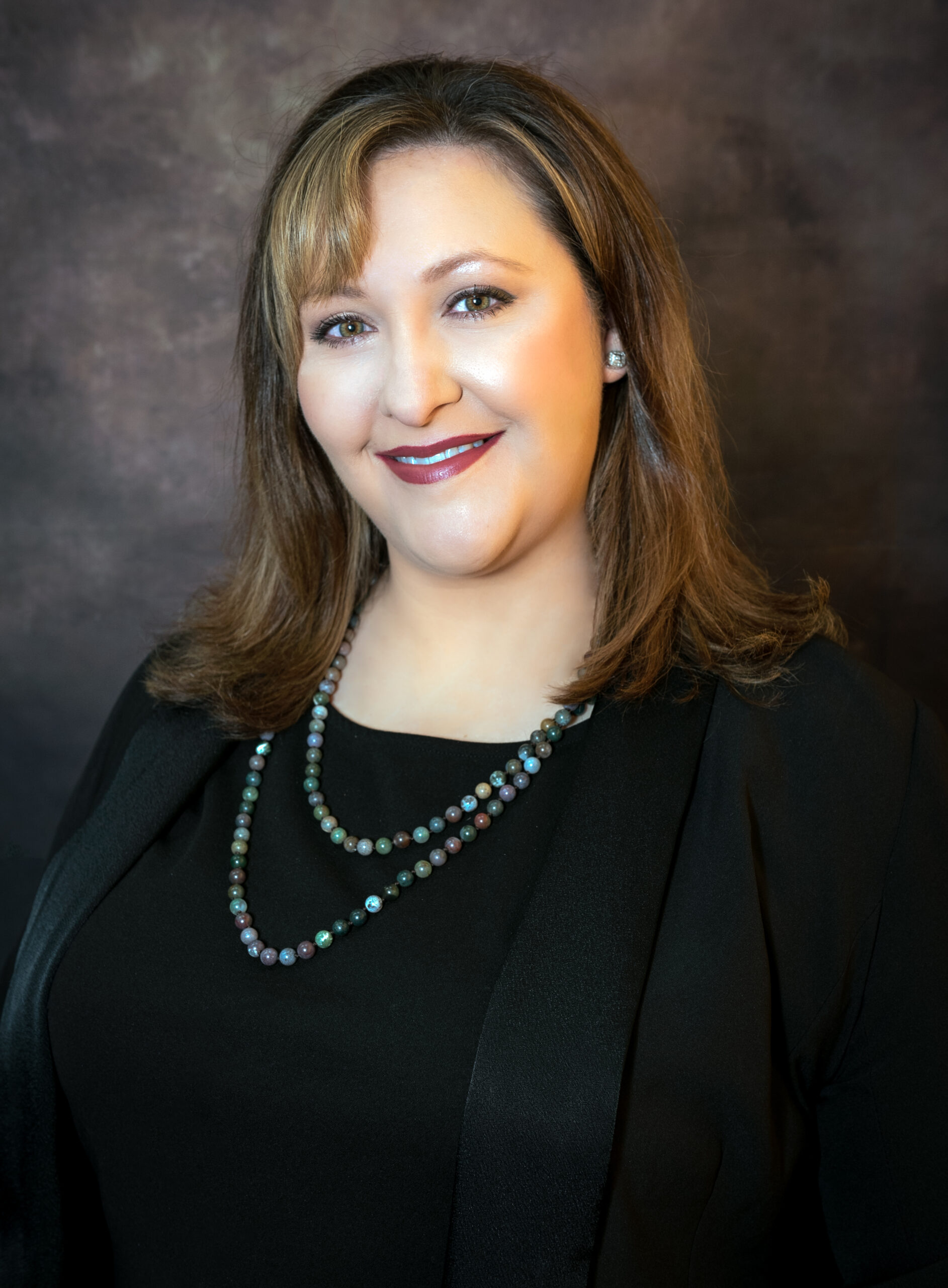 Lady in black suit in front of dark background