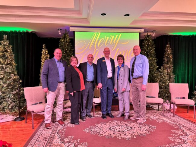panel of speakers surrounded by Christmas trees